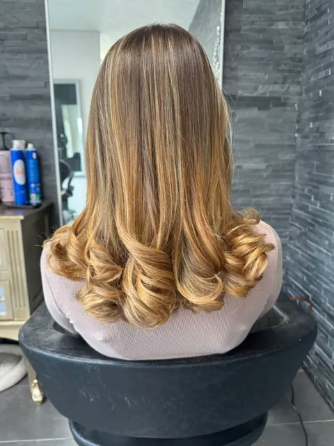 Balayage caramel lumineux et brushing aux pointes bouclées, au salon Et Voilà à Fribourg