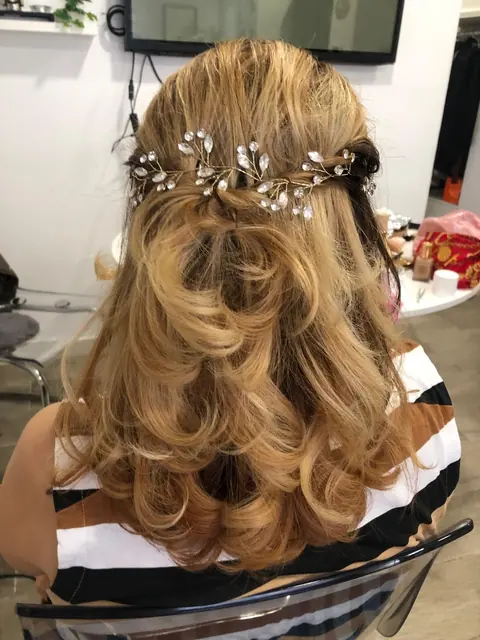 Coiffure de cérémonie demi-attachée sur cheveux blonds ondulés, avec bijou de cheveux en cristal