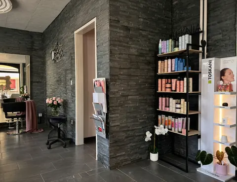 Intérieur du salon Et Voilà, murs en pierre grise et produits capillaires