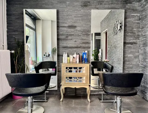 Fauteuils de coiffage et murs en pierre du salon Et Voilà