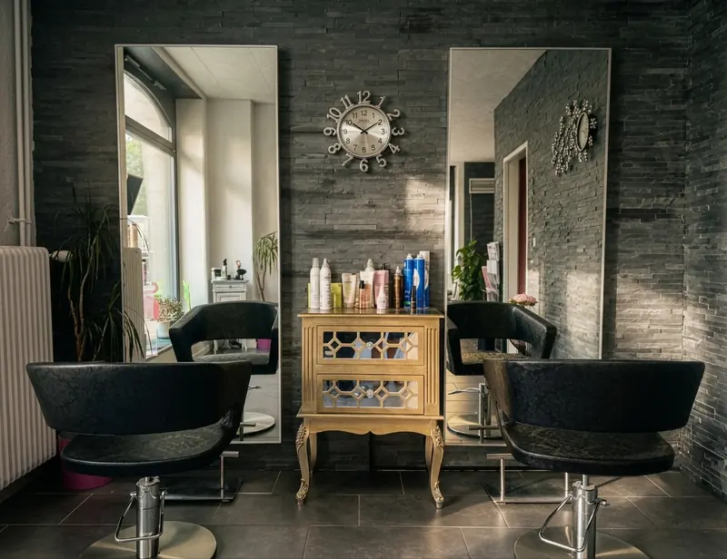 Postes de coiffage du salon Et Voilà avec miroirs et fauteuils noirs